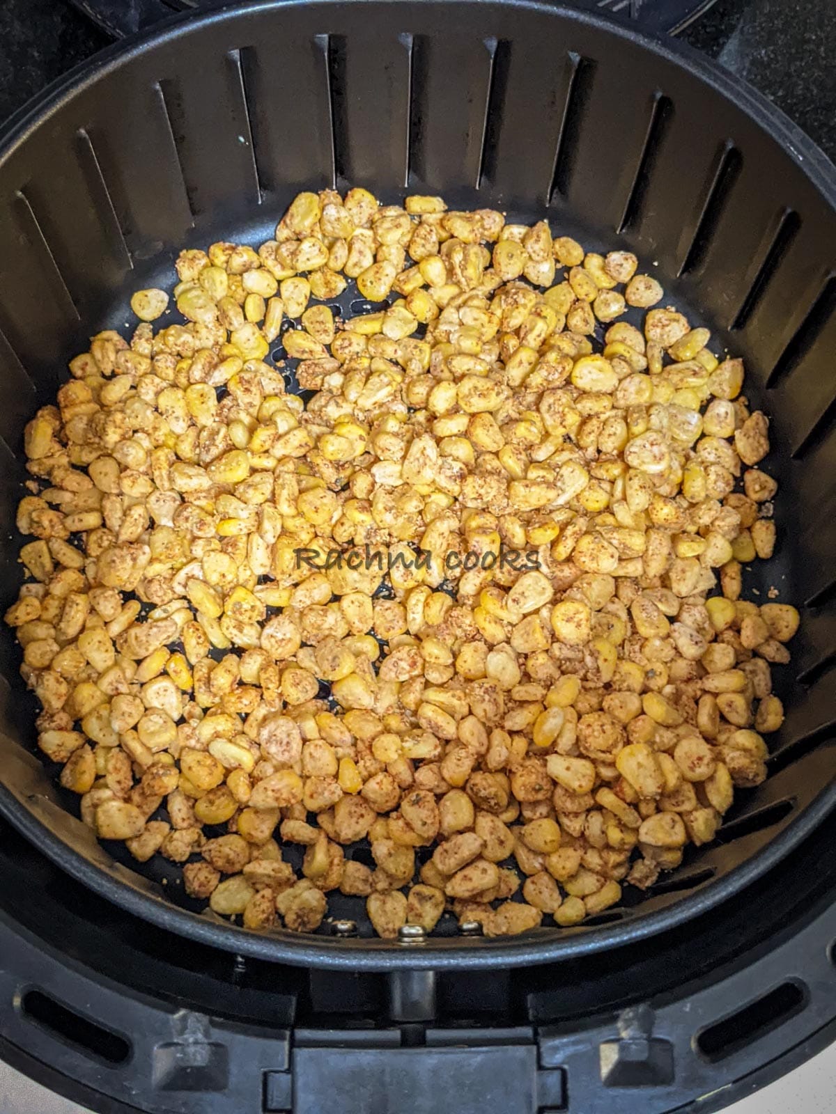 Coated corn placed in air fryer basket ready for air frying.