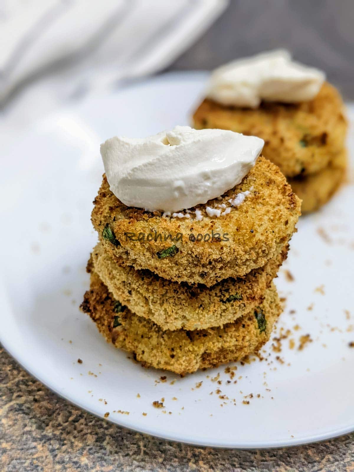 3 potato pancakes on top of each other topped with sour cream