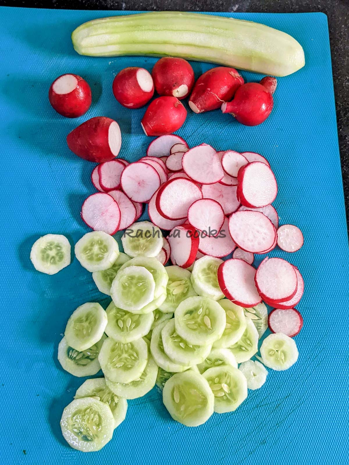 Sliced cucumbers and radishes on a chopping board.