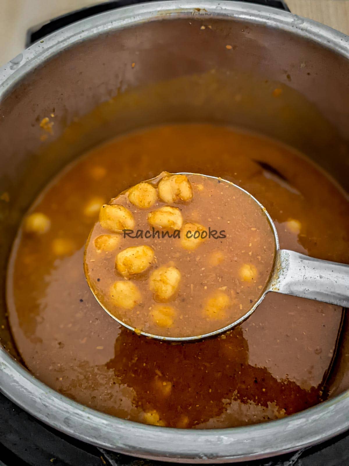 A ladle showing chana masala or chole curry on top of Instant pot.