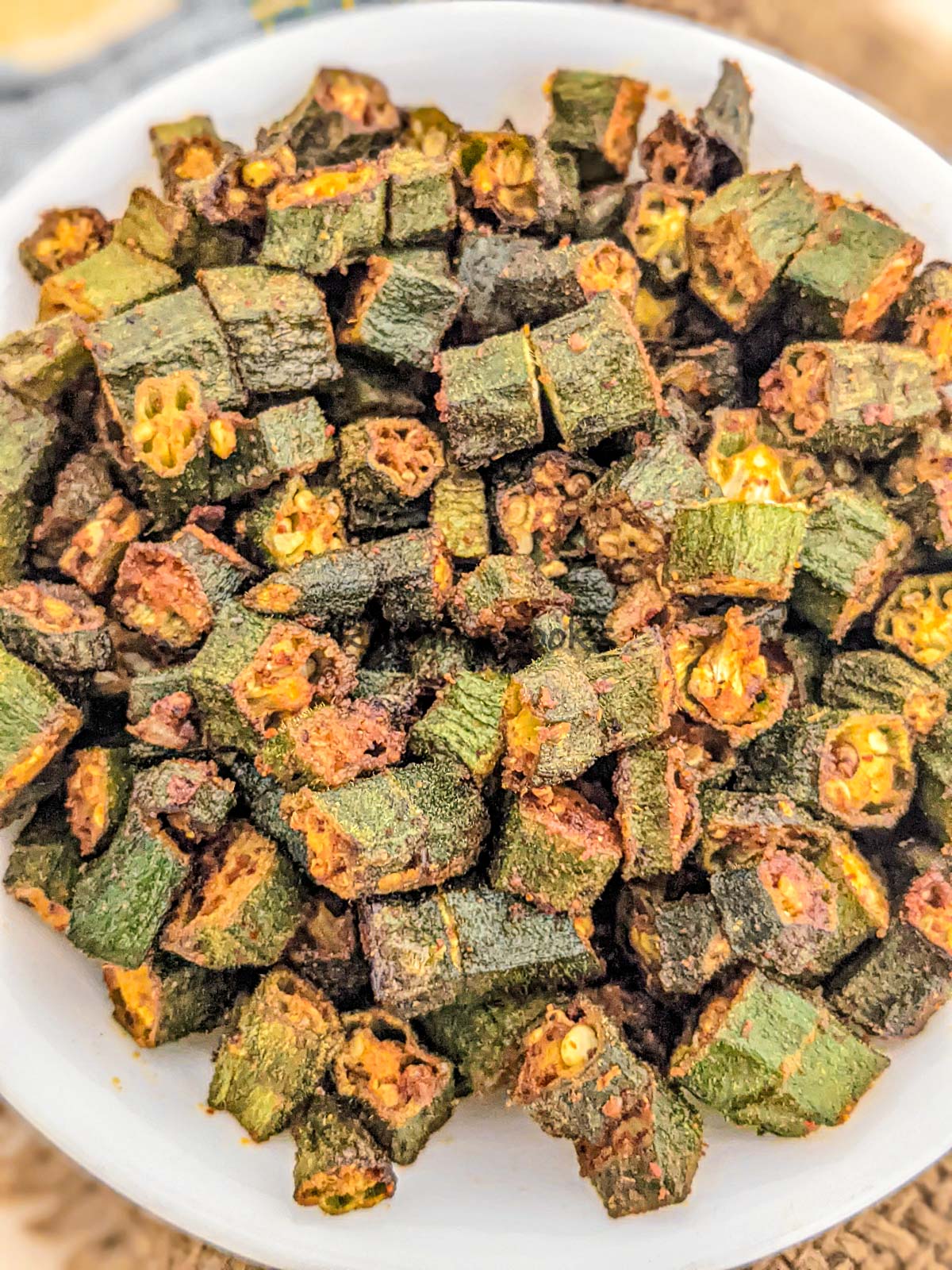 Fried okra in air fryer on a white plate, top shot.