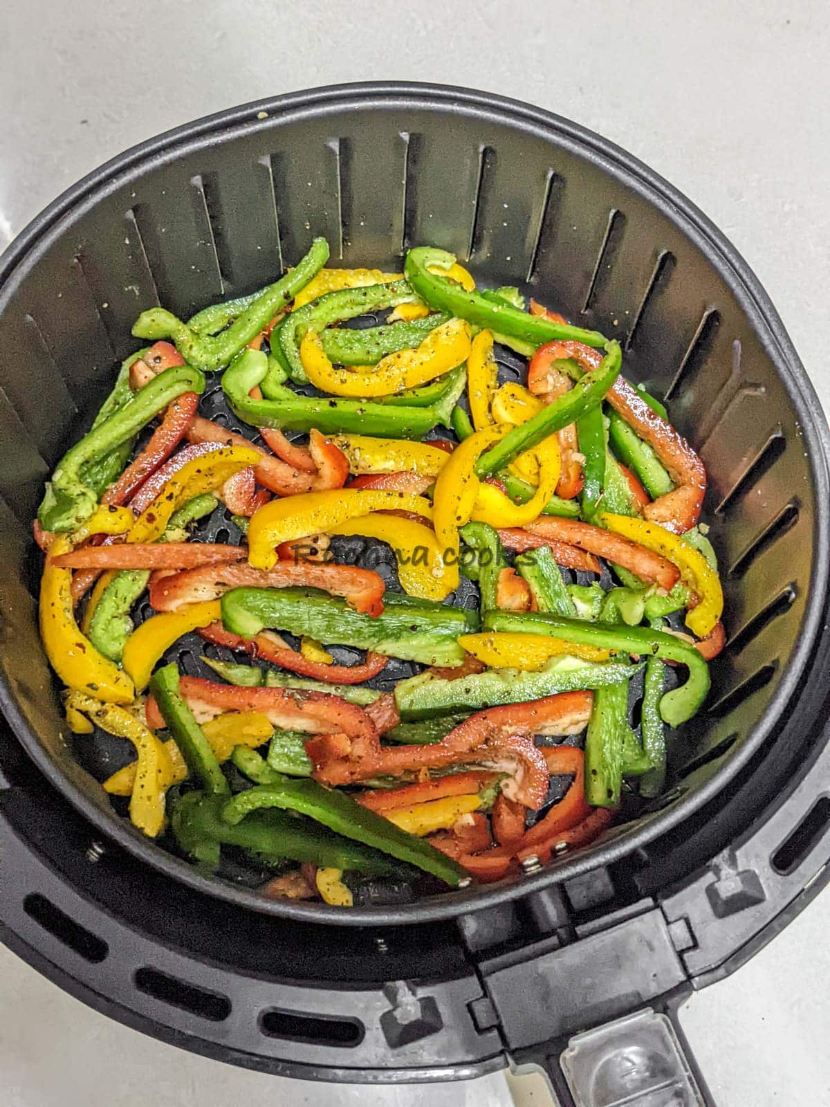 Marinated peppers in air fryer basket ready for air frying.