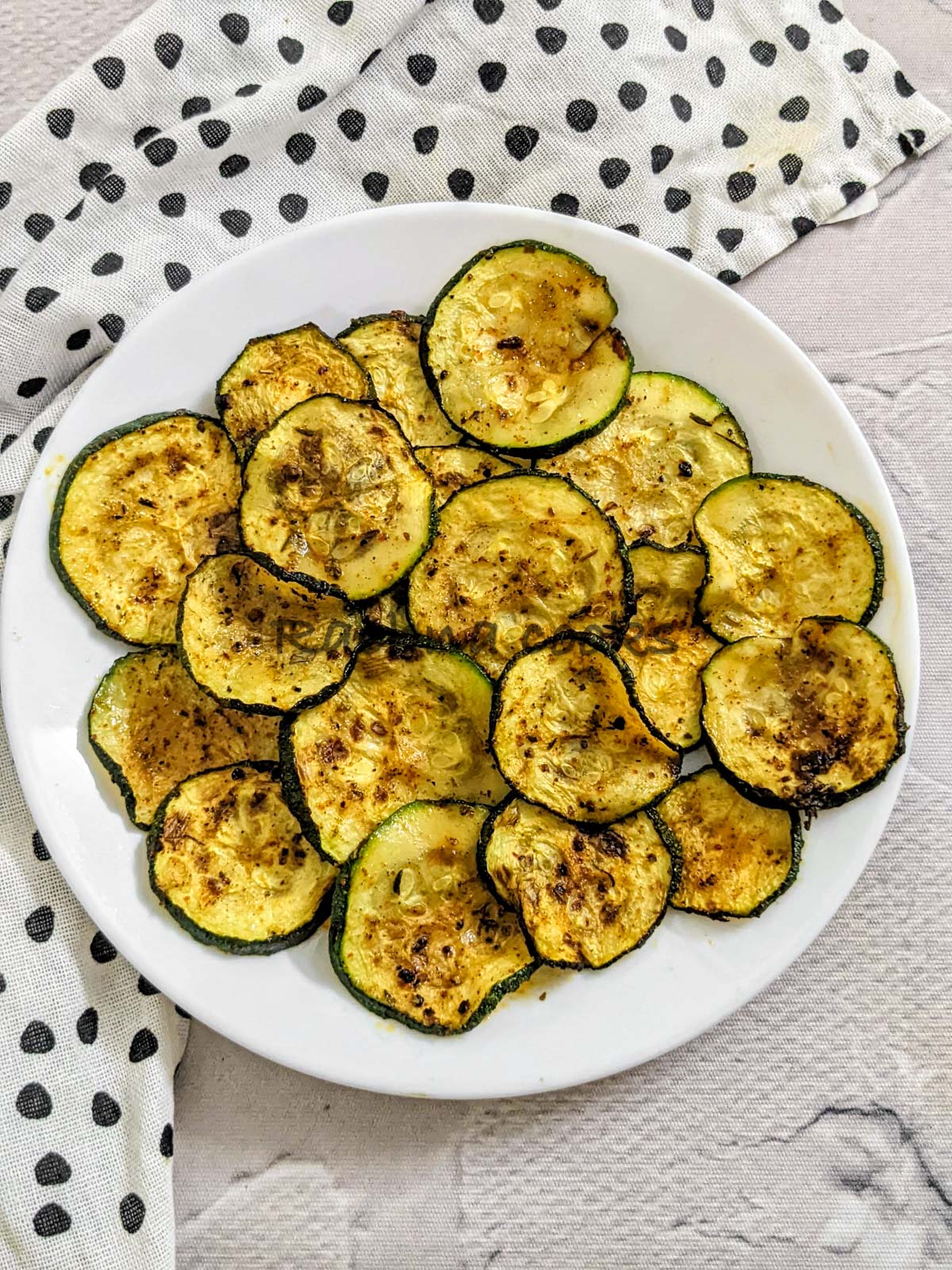 air fried zucchini chips on a white plate.