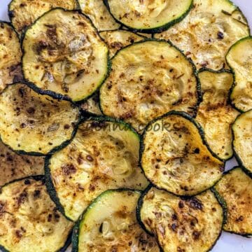 Close up of air fried zucchini chips on a white plate