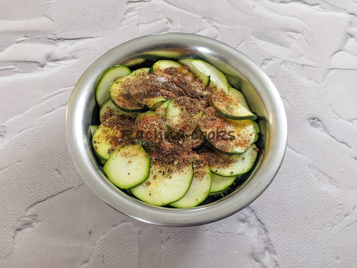 zucchini slices with spices and oil in a bowl