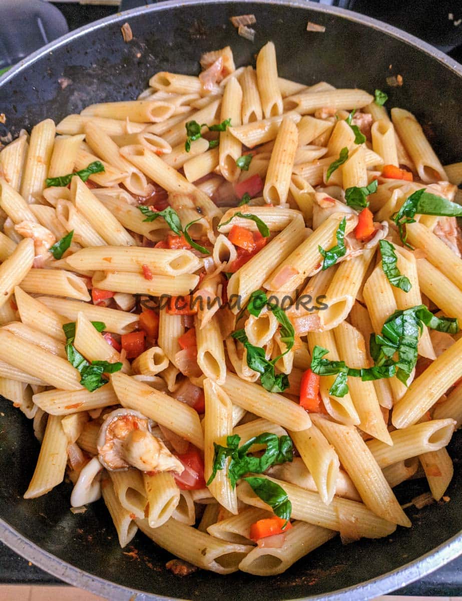 Pasta in red sauce in a large wok.
