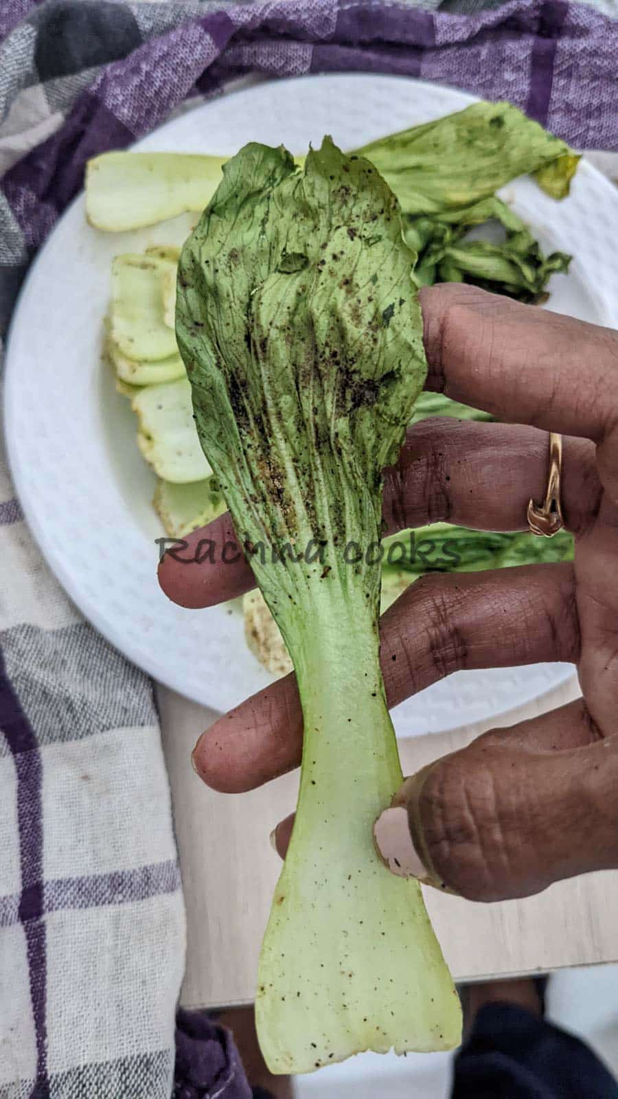 One bok choy leaf held in hand after air frying.