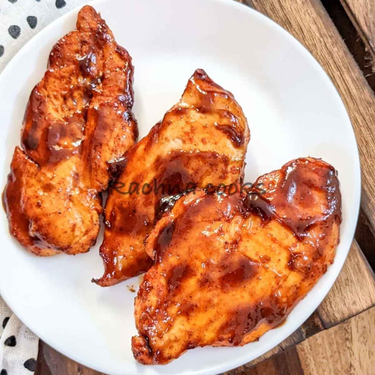 Close up of BBQ chicken breasts on a white plate.