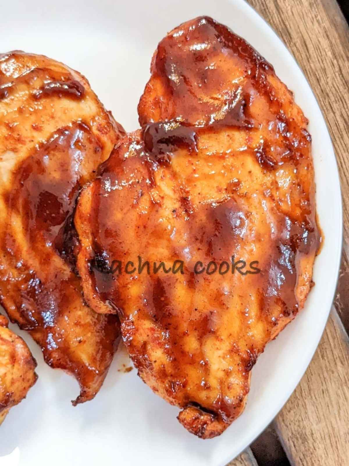 Close up of BBQ chicken breast on a white plate.