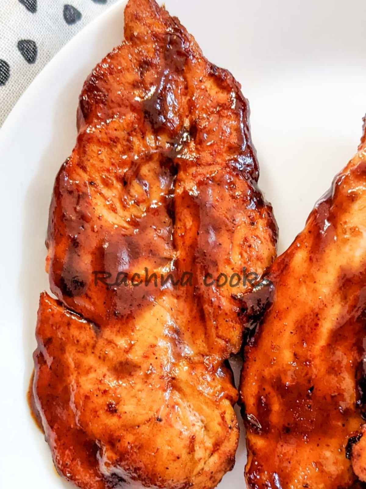 Close up of BBQ chicken breast on a white plate.