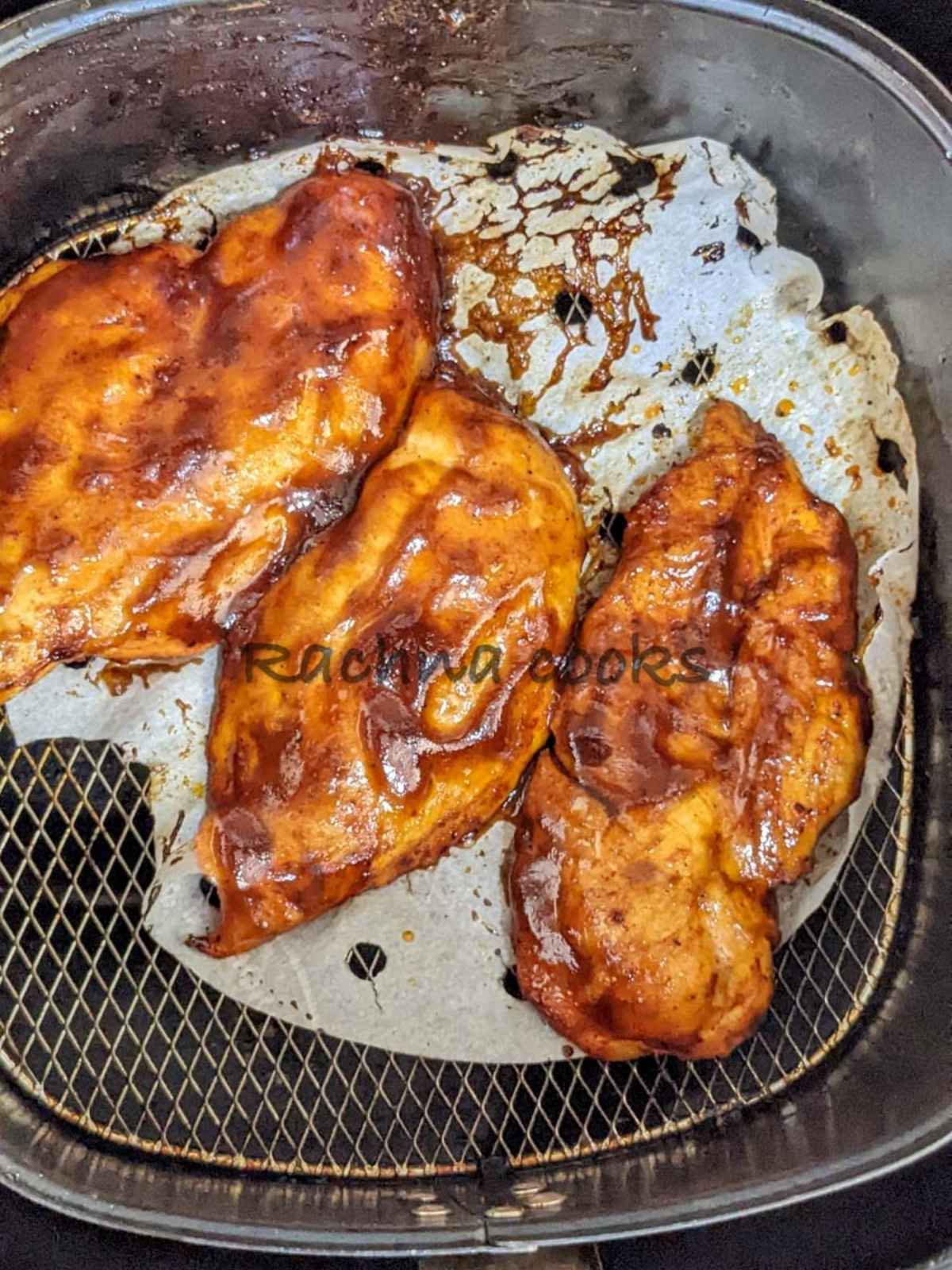 Chicken fillets with BBQ sauce in air fryer basket.