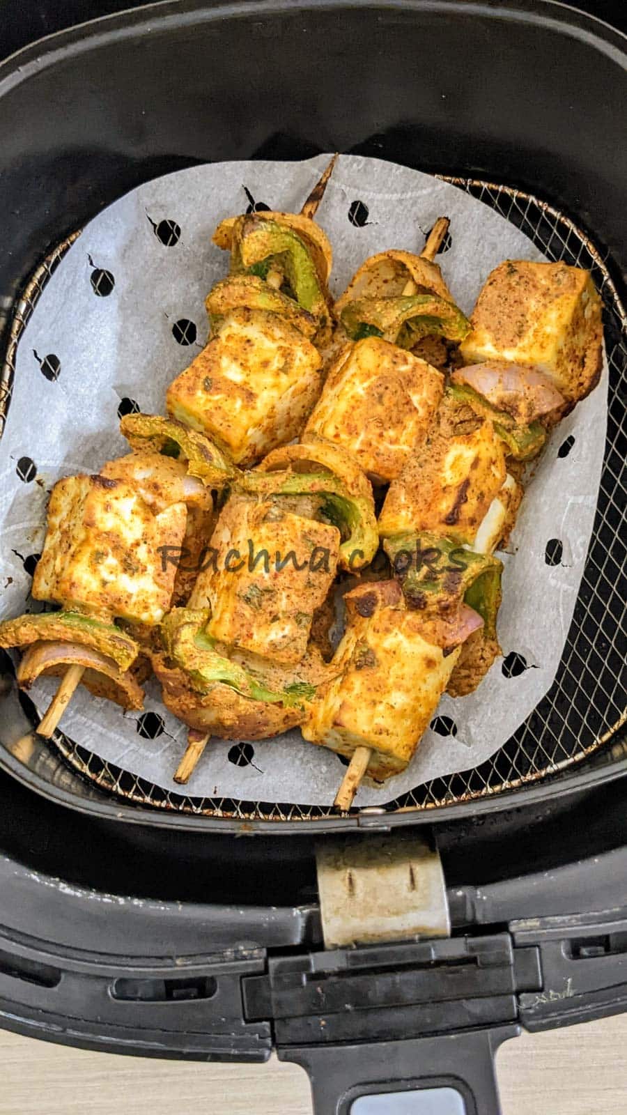 Skewers of air fried paneer tikka in air fryer basket.