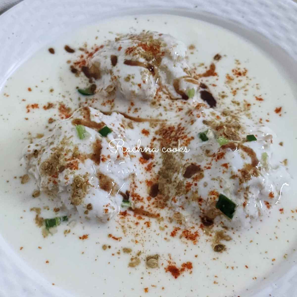 Dahi vadas served on a white plate.