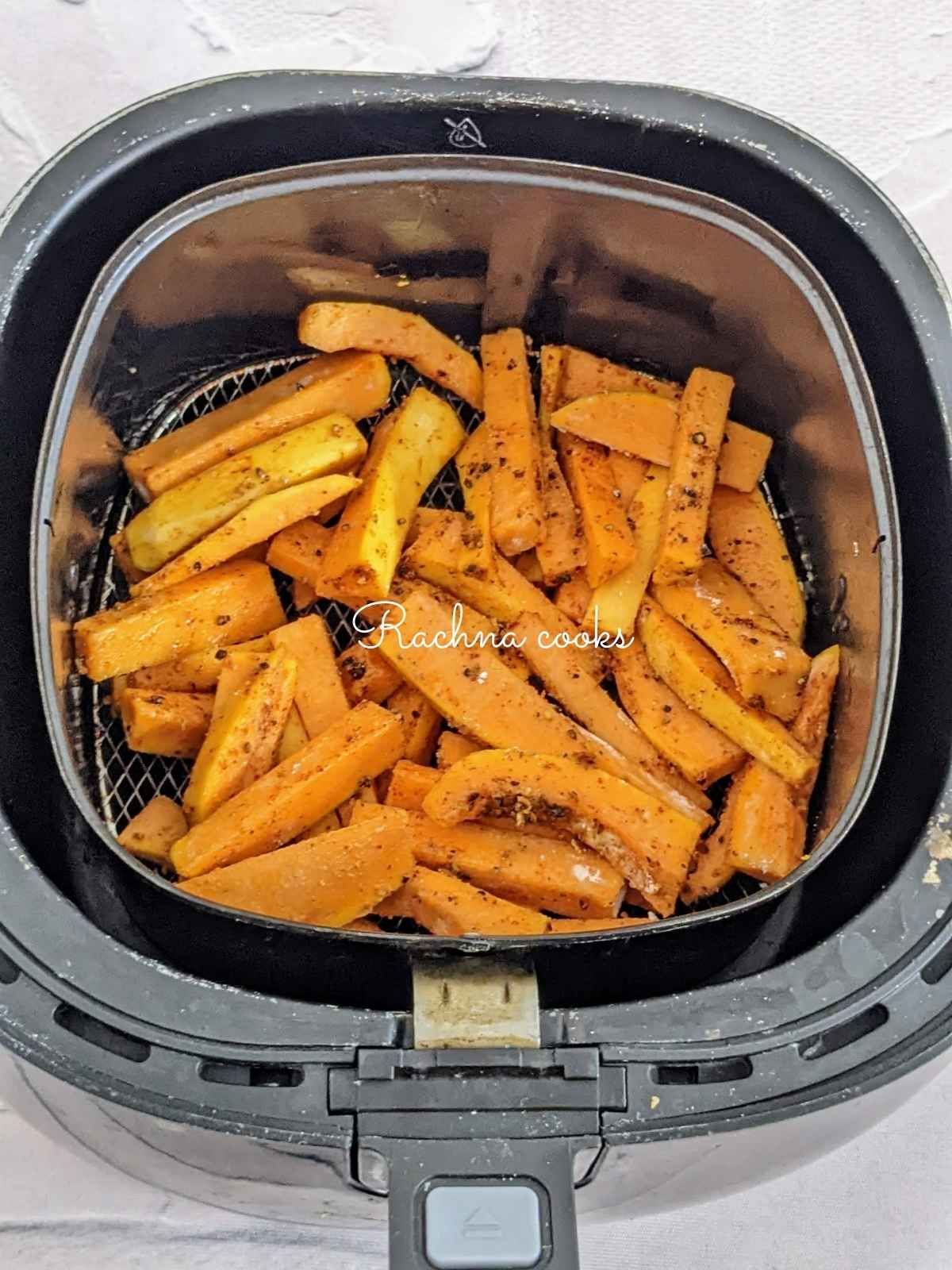 Seasoned butternut squash fries placed in air fryer basket for air frying