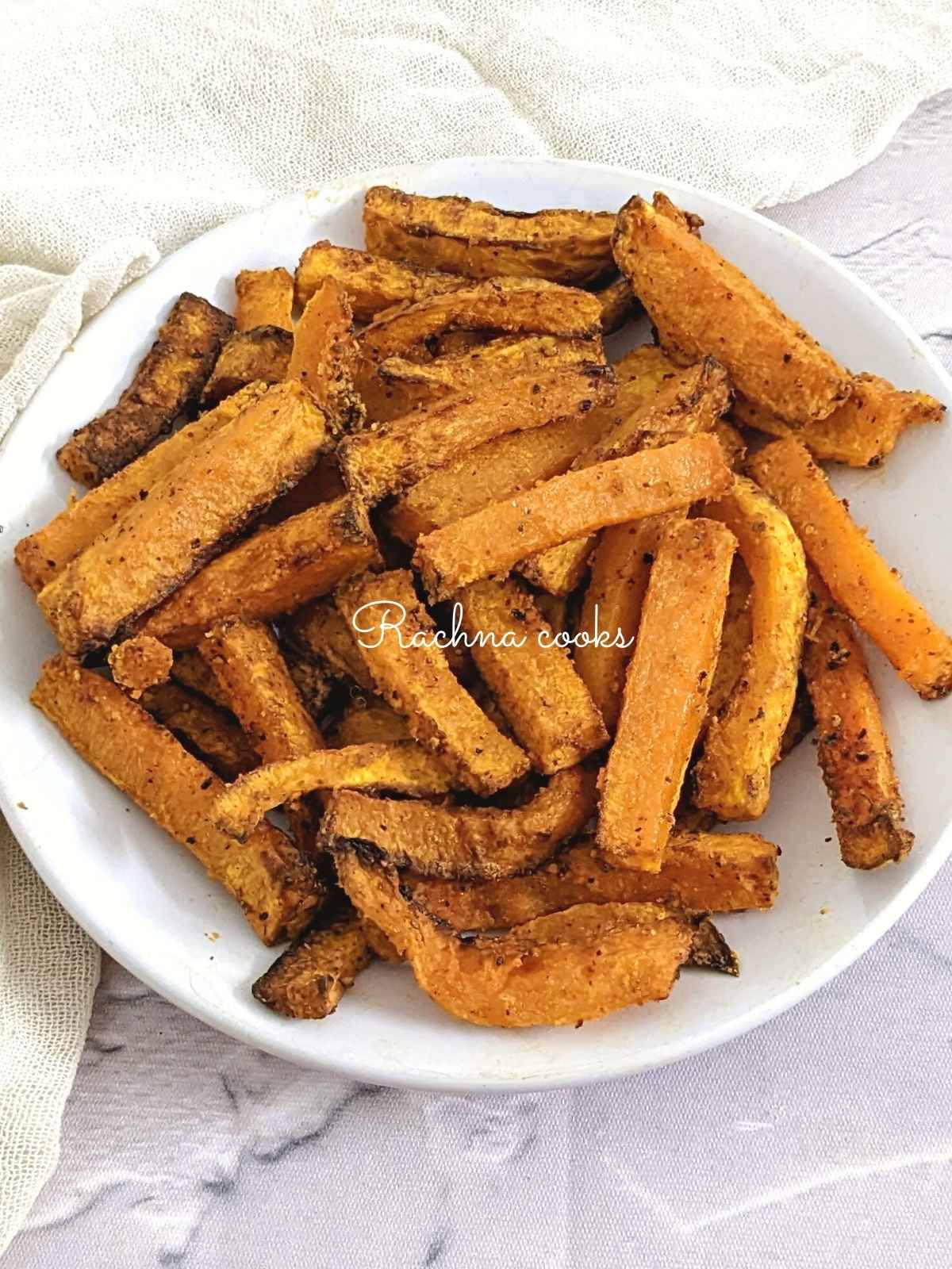 Close up of air fryer butternut squash fries on a white plate