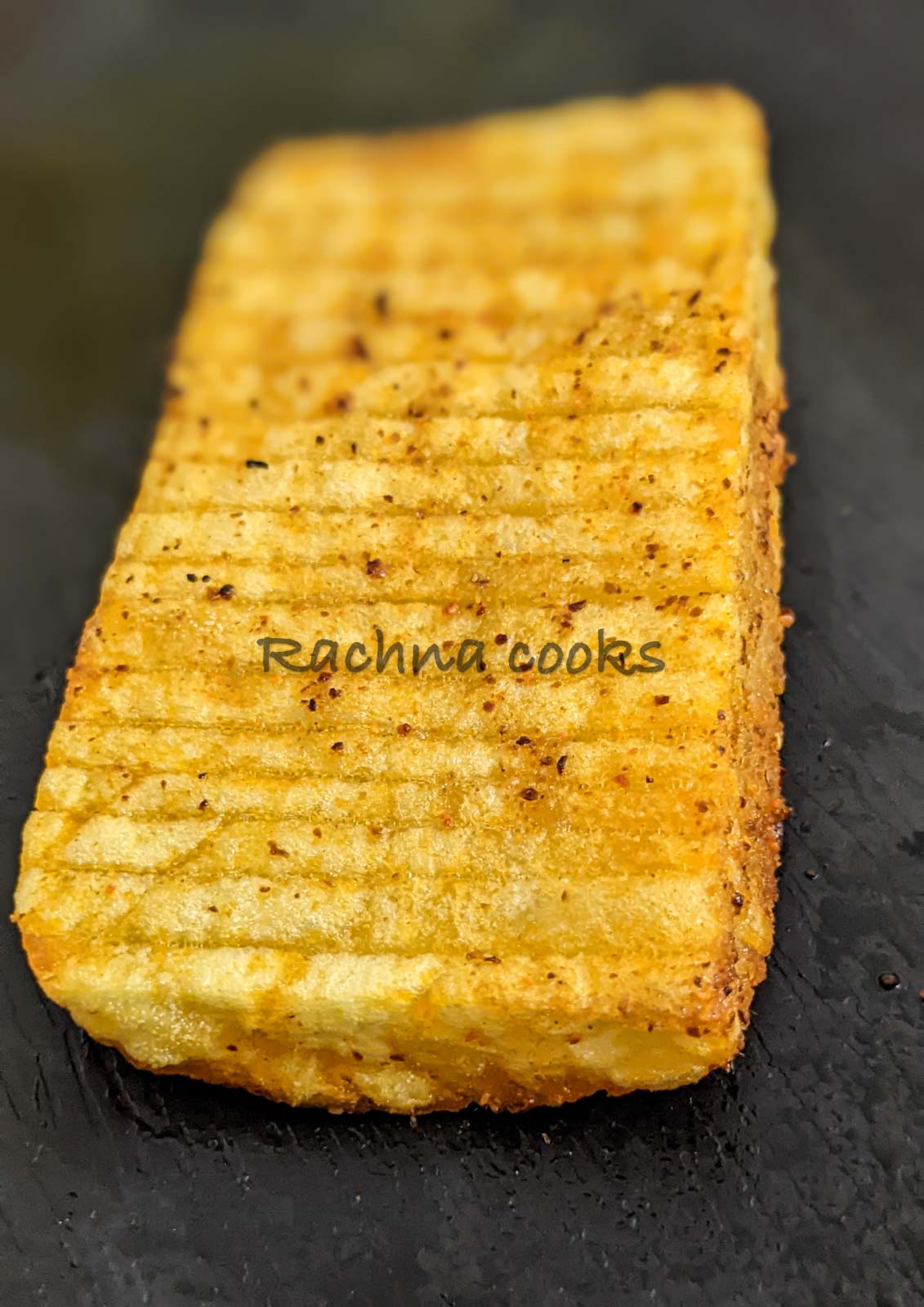 Close up of accordion potato on black plate
