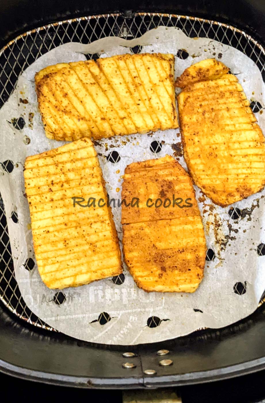 Accordion potatoes after air frying in air fryer basket.