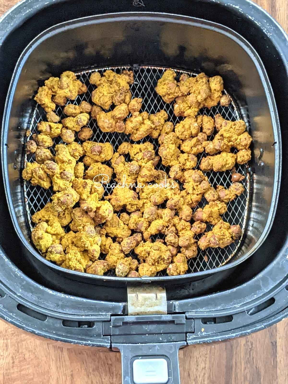 Coated masala peanuts done after air frying placed in air fryer basket.