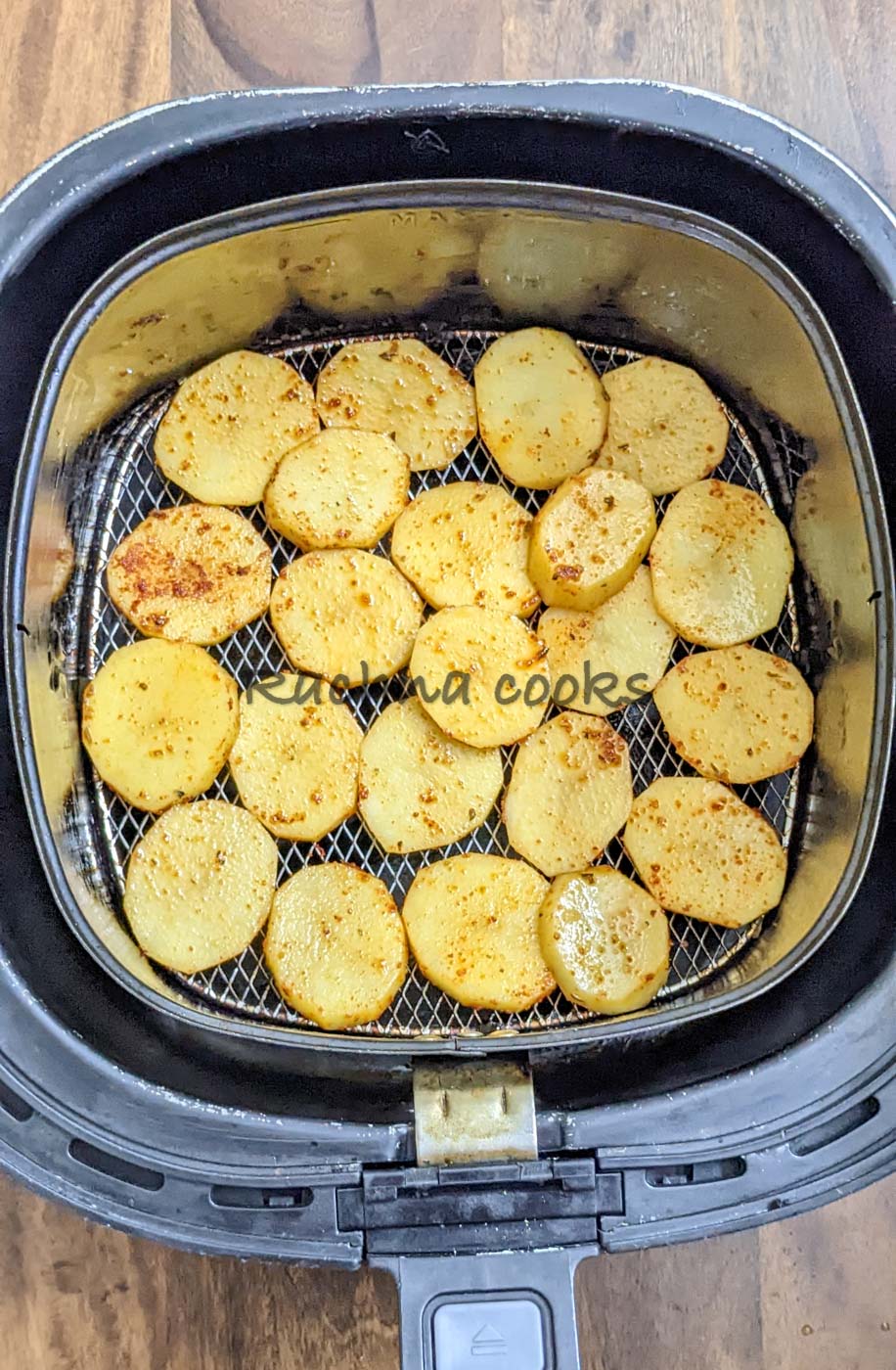 Potato slices in air fryer basket for cooking.