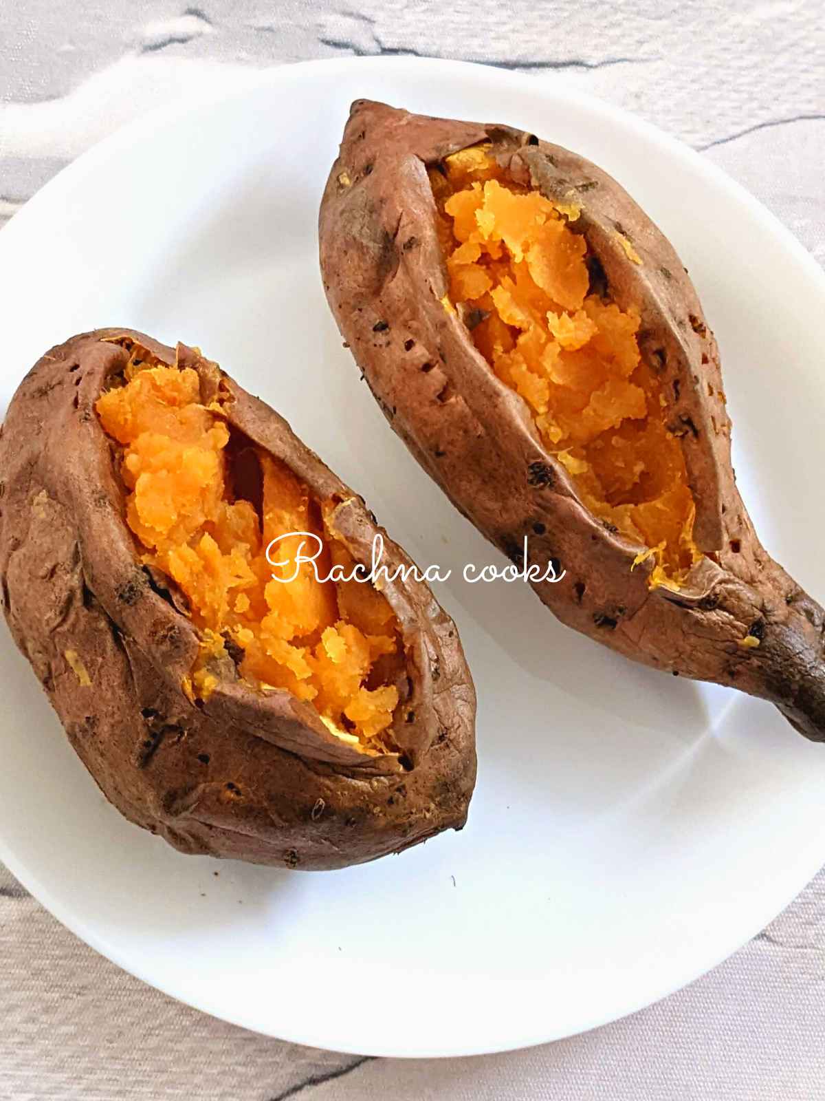 Two large air fried baked sweet potato with wrinkly skin and fluffy flesh on a white plate.