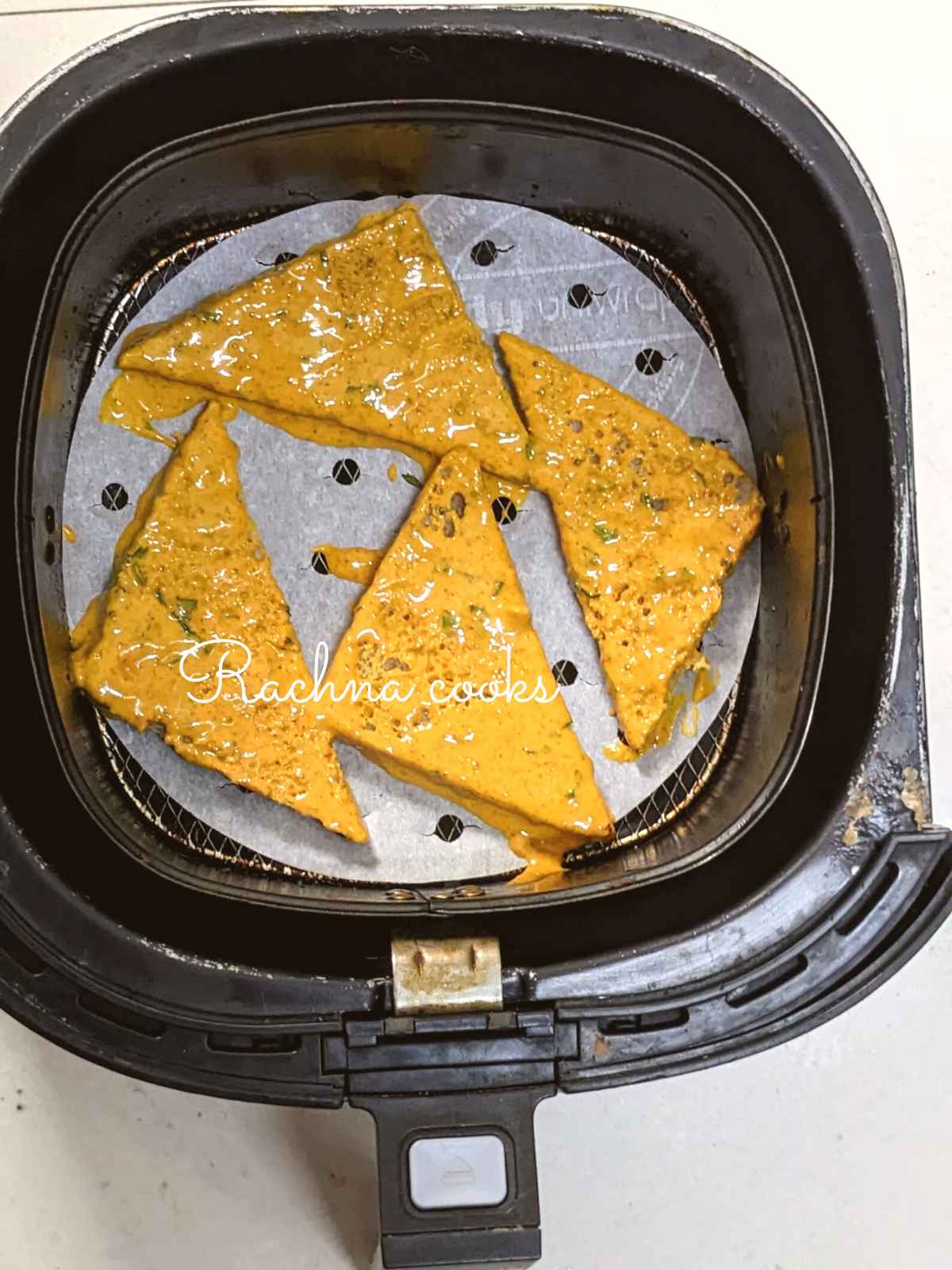Chickpea flour batter coated bread slice triangles placed in air fryer basket.