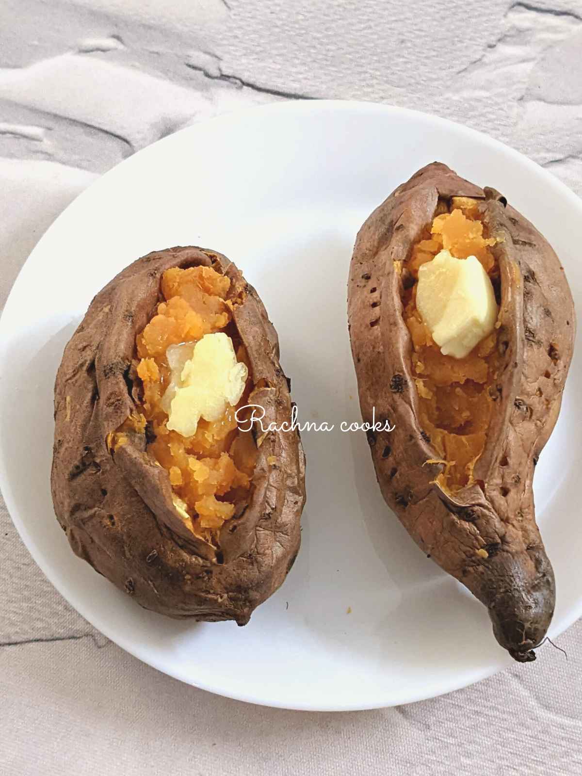 Two large air fried baked sweet potato with wrinkly skin and fluffy flesh with a blob of butter on top.