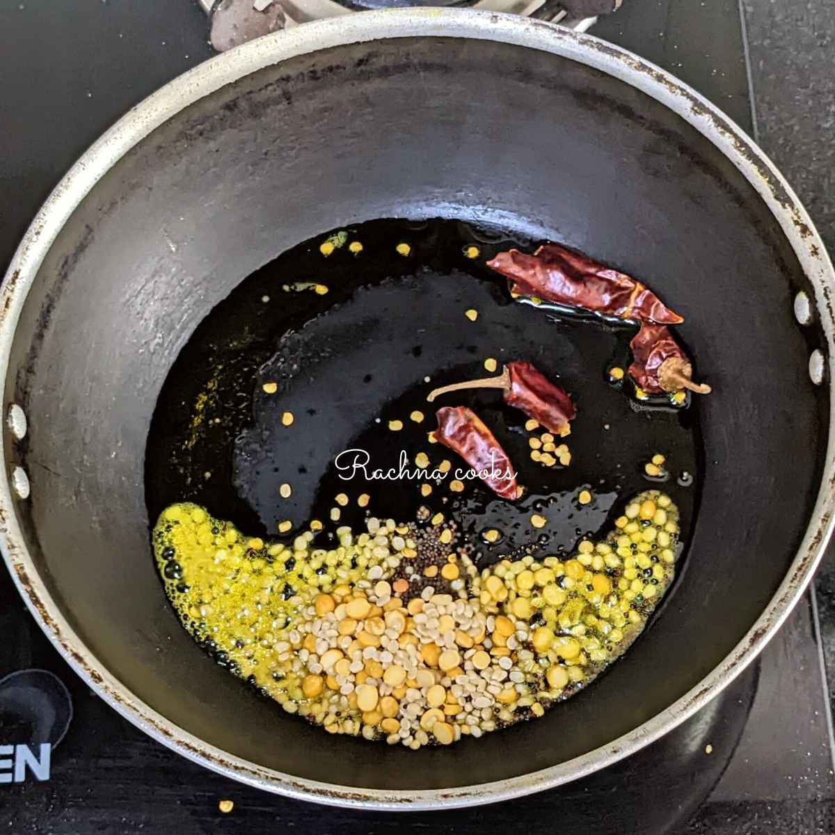 Oil with lentils, mustard seeds and broken dry red chillies in a wok.