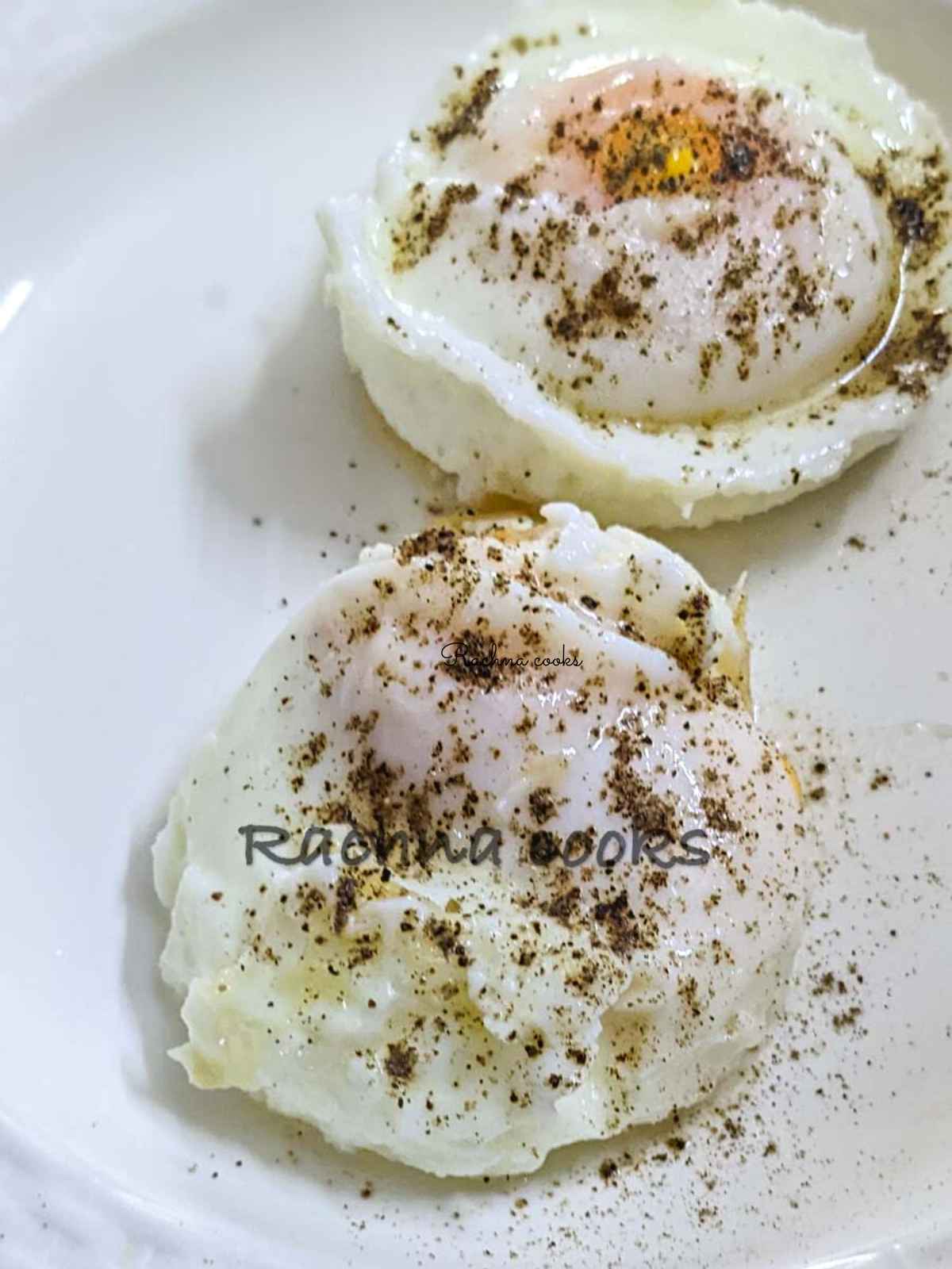 Close up of 2 poached eggs garnished with salt and pepper on a white plate.