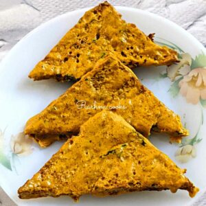 3 bread pakora triangles touching each other on a white plate.
