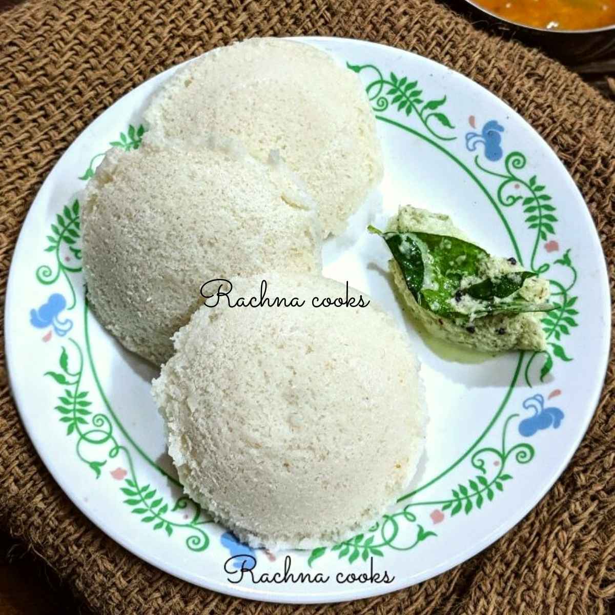 3 idlis served on a white plate with coconut chutney.