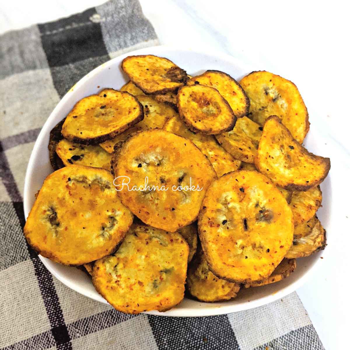Golden red plantain chips after air frying in a brown bowl.