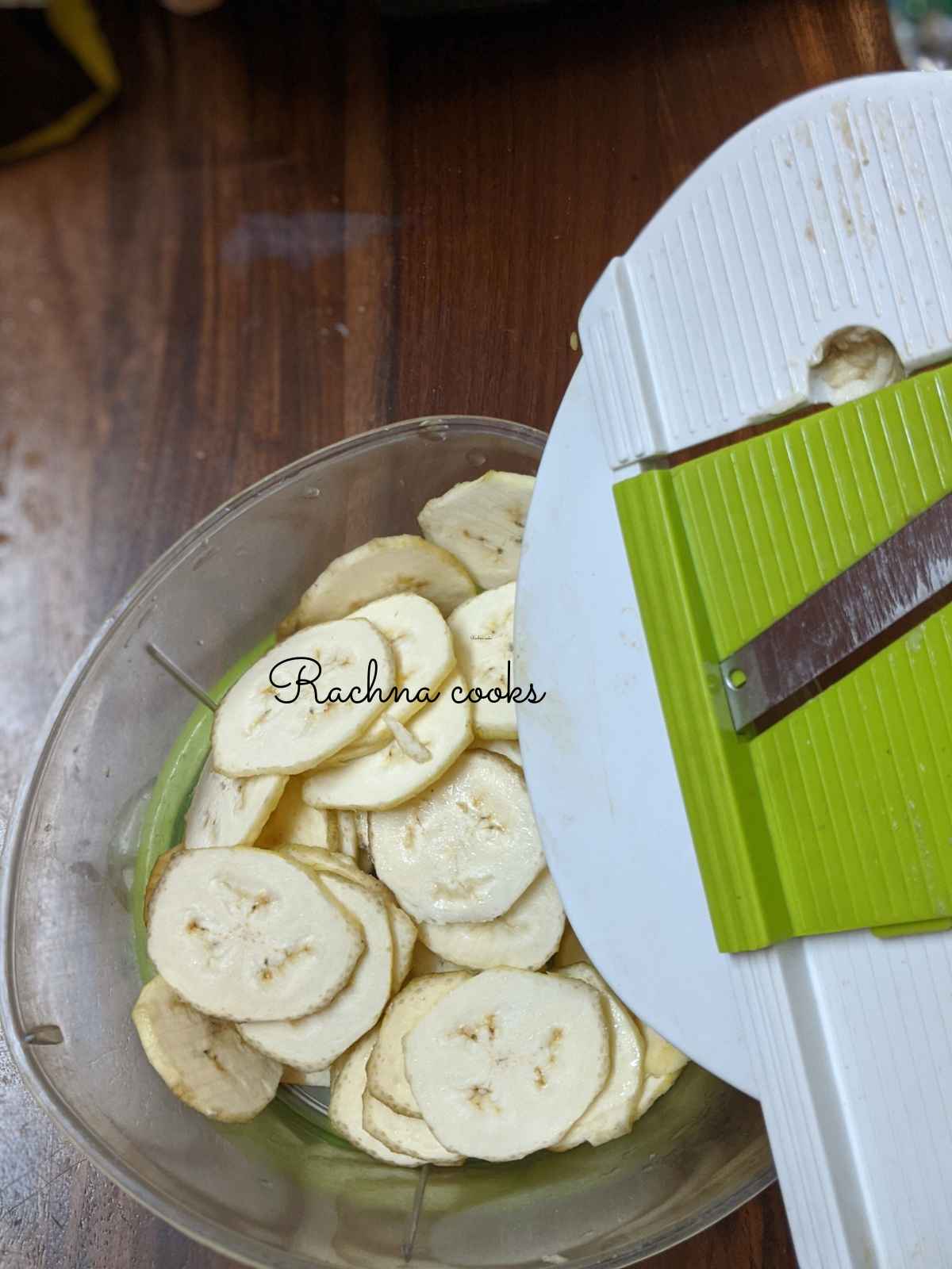 Plantain chips in a bowl with a mandolin slicer visible.
