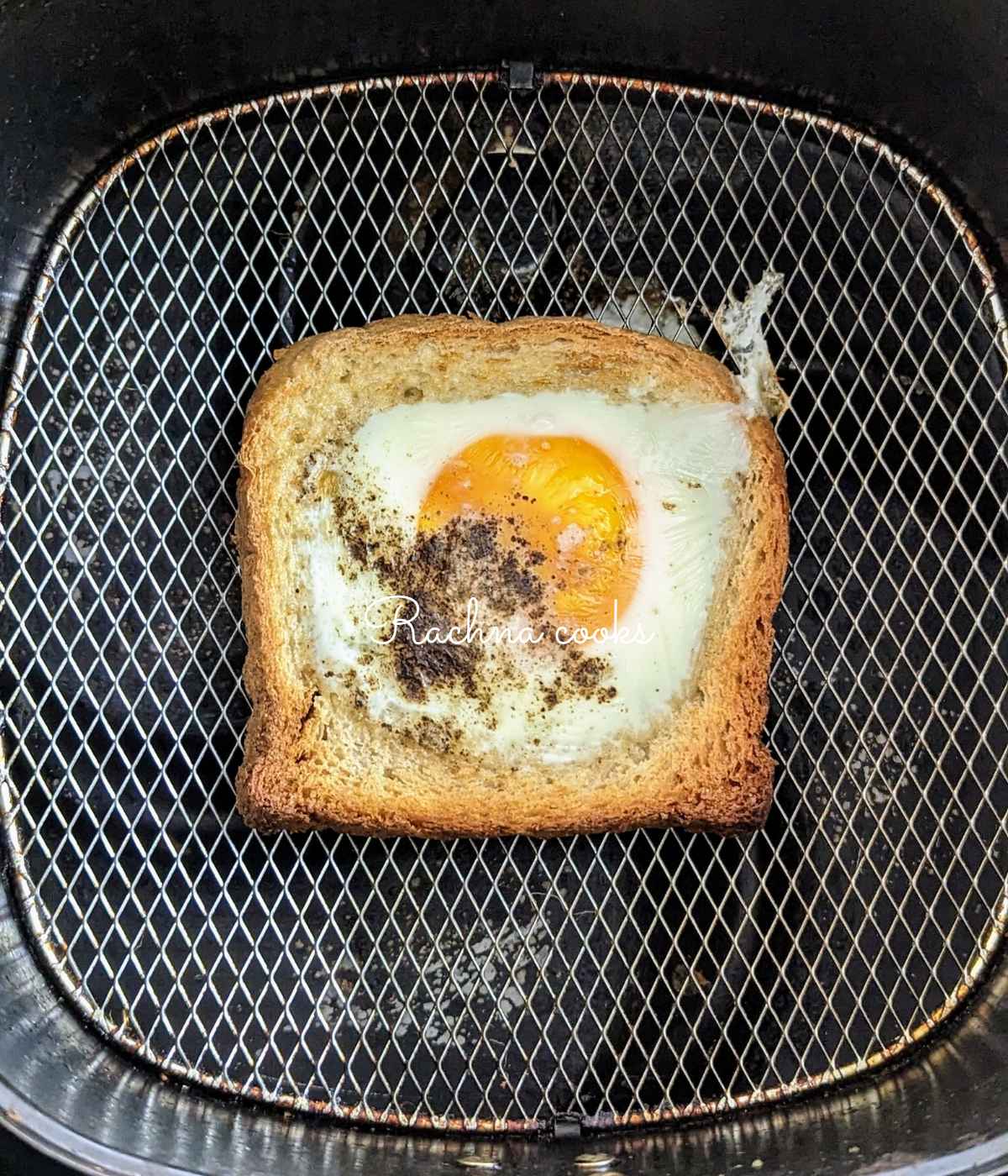 Egg toast with salt and pepper on air fryer basket.