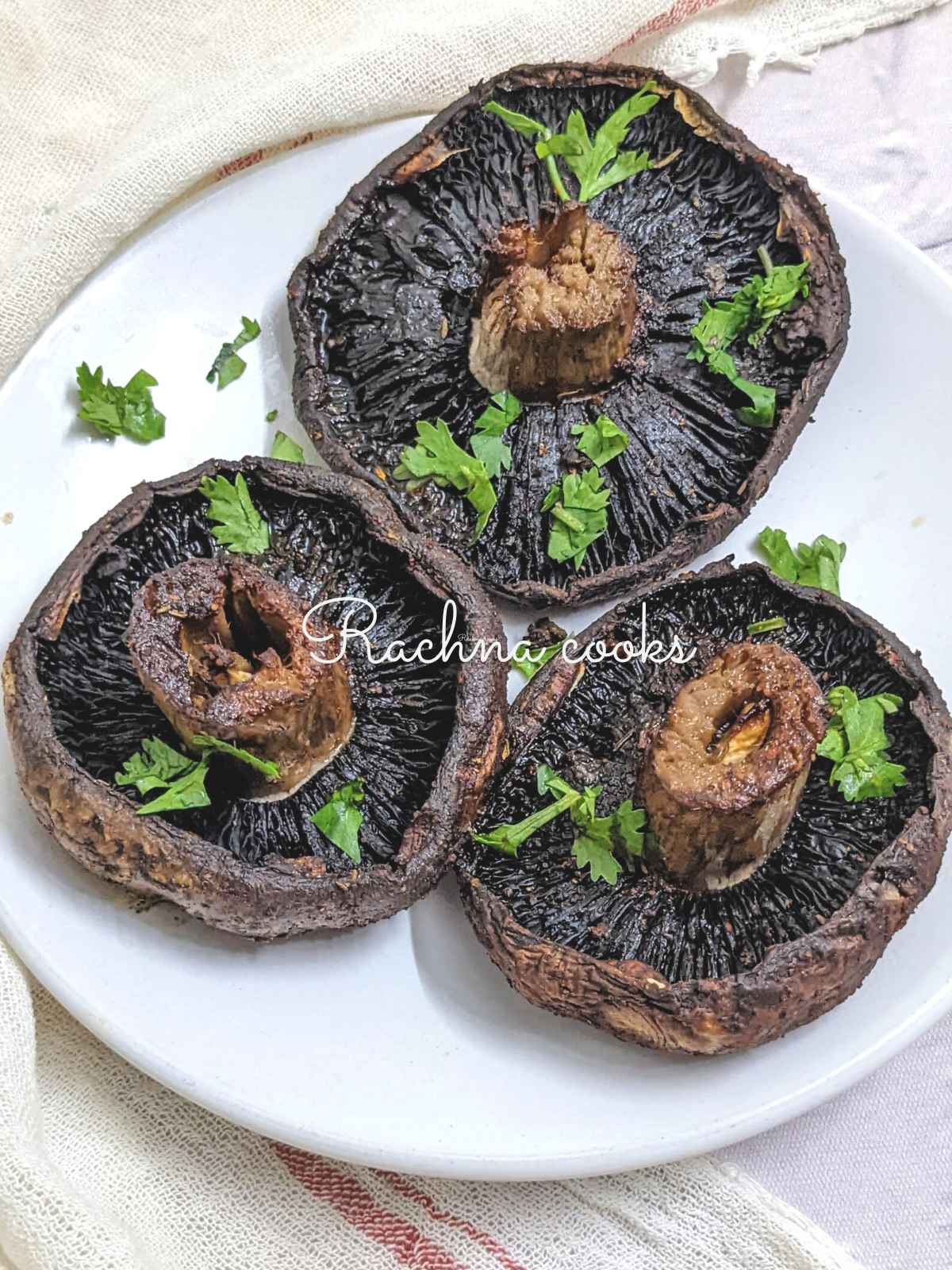 3 delicious air fried portobello mushrooms stalk side up on a glass plate garnished with cilantro