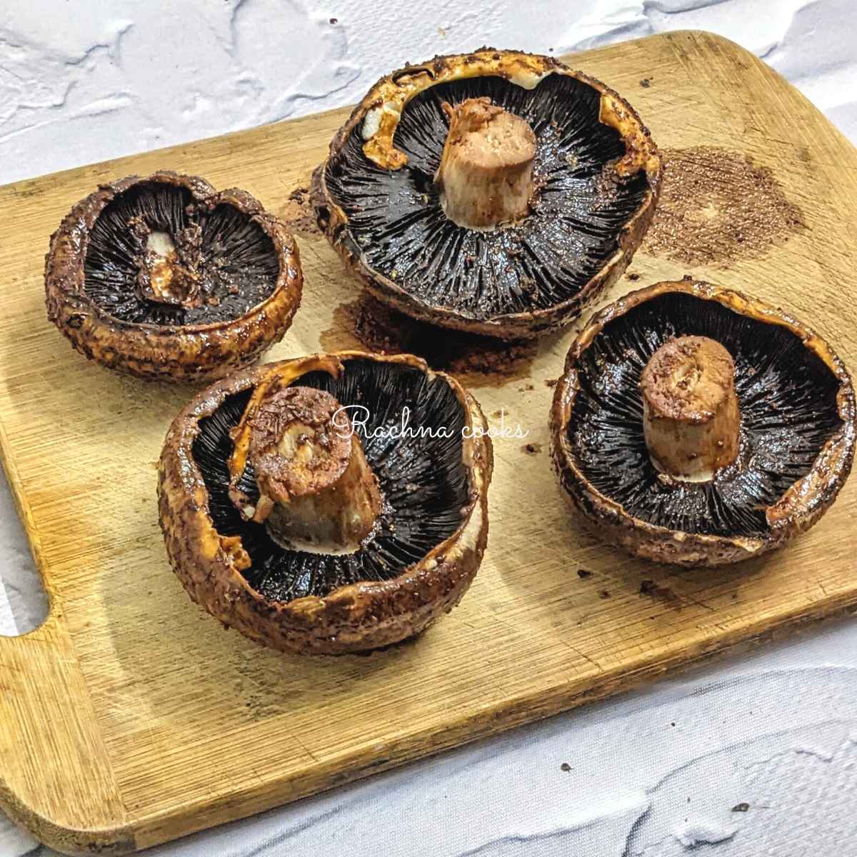 Marinade applied on both sides of portobello mushrooms and kept stalk side up on a chopping board.