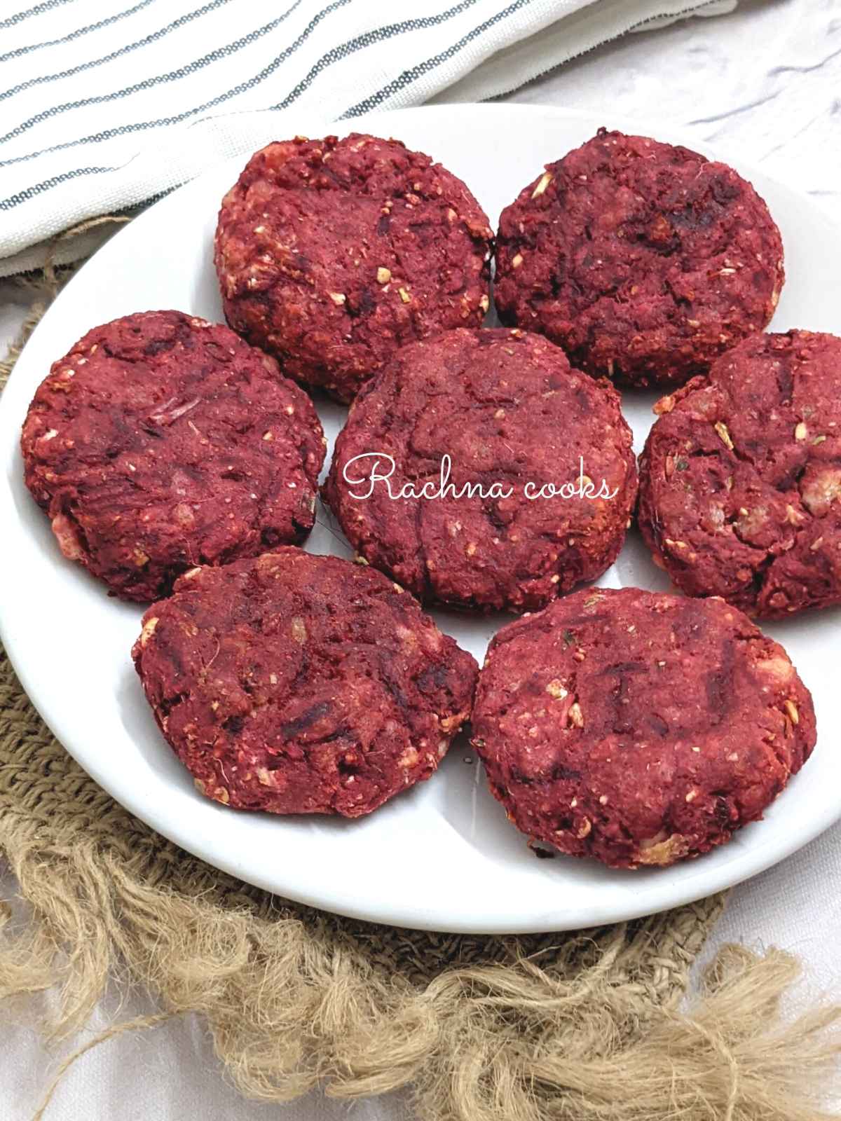 7 beetroot tikkis on a white plate.