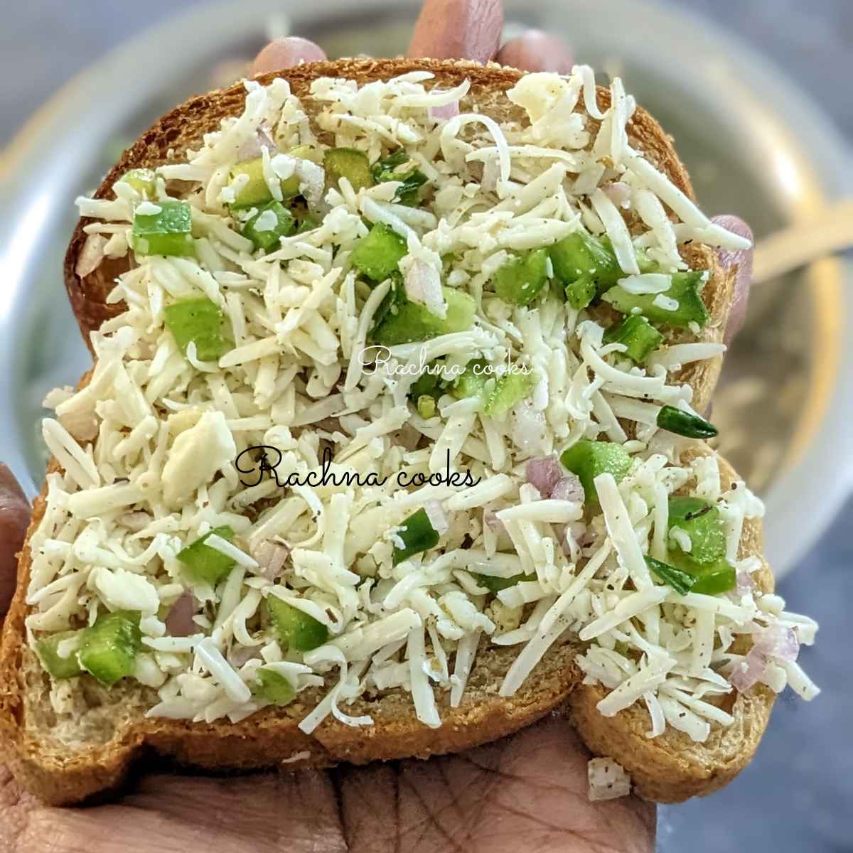 One toast topped with cheesy topping held up in hand.