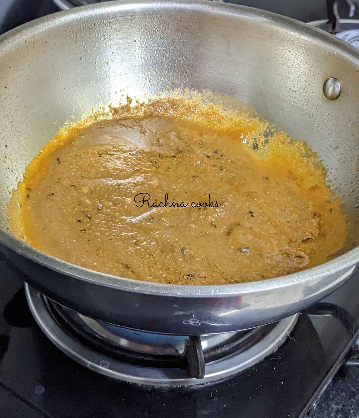 Tomato and other herbs masala paste  being cooked in a pan.