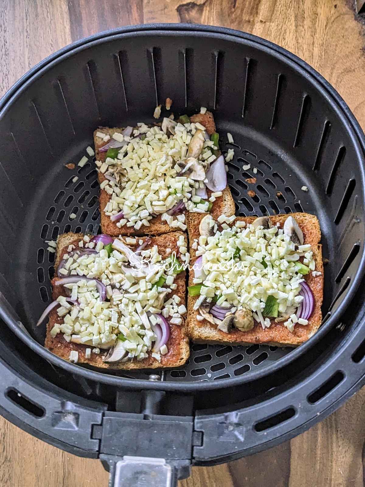 3 slices of bread pizza in air fryer basket.