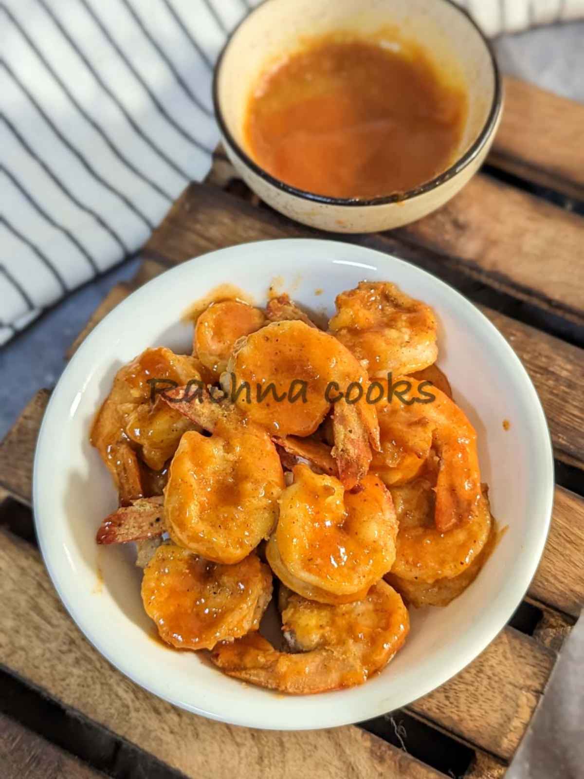 Air fried buffalo shrimp in a white bowl with a bowl of Buffalo sauce served along with it.