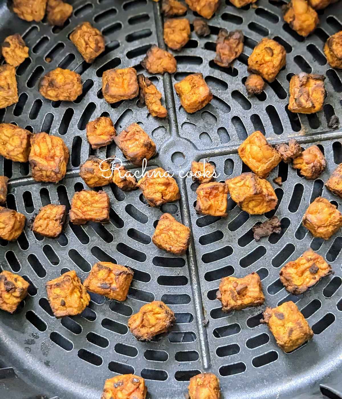 Air fried tempeh cubes in air fryer basket.