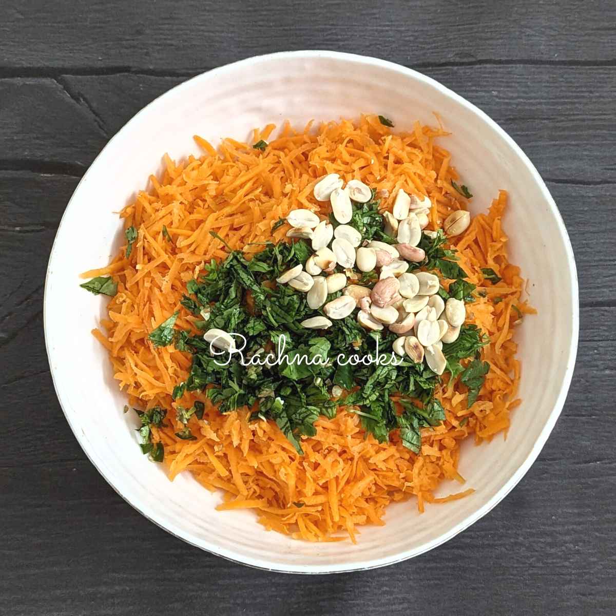 Grated carrot, chopped cilantro, chilli and roasted peanuts in a bowl.