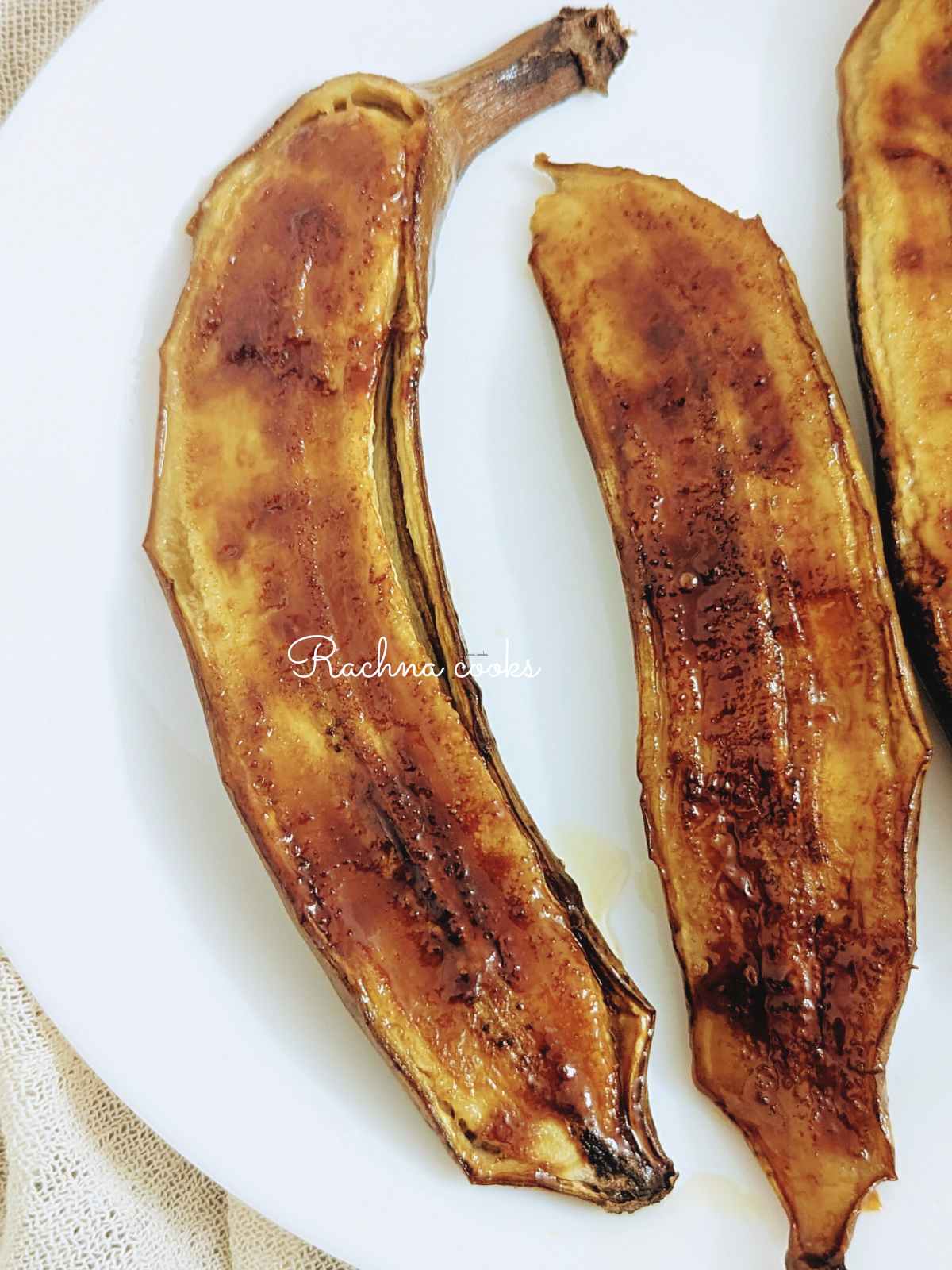 2 Caramelised air fryer banana halves on a white plate.