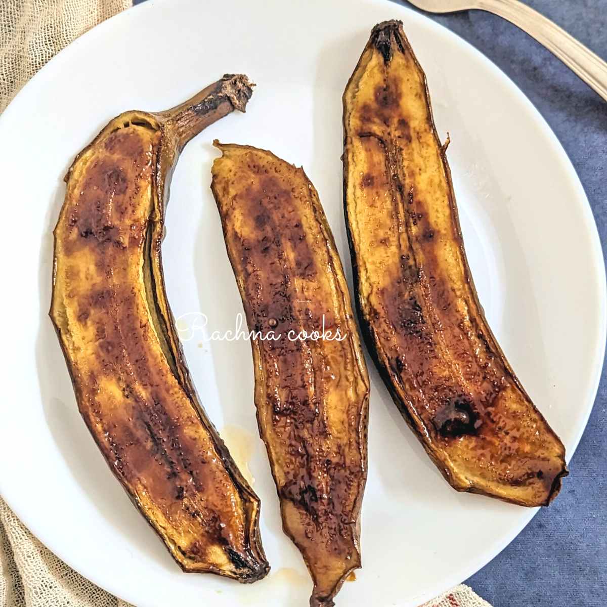 3 air fried banana halves served on a white plate.