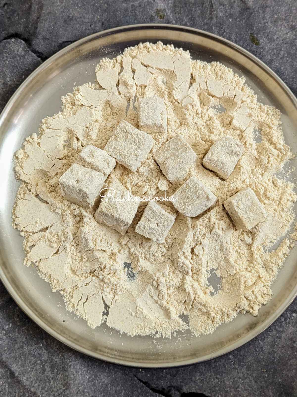 tofu bites immersed in flour in a shallow plate