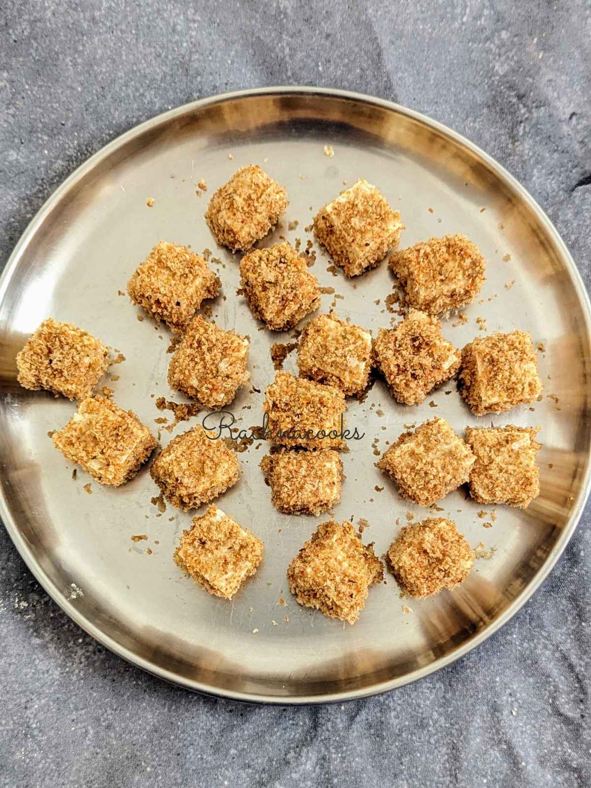 Tofu bites after breading in a shallow plate.