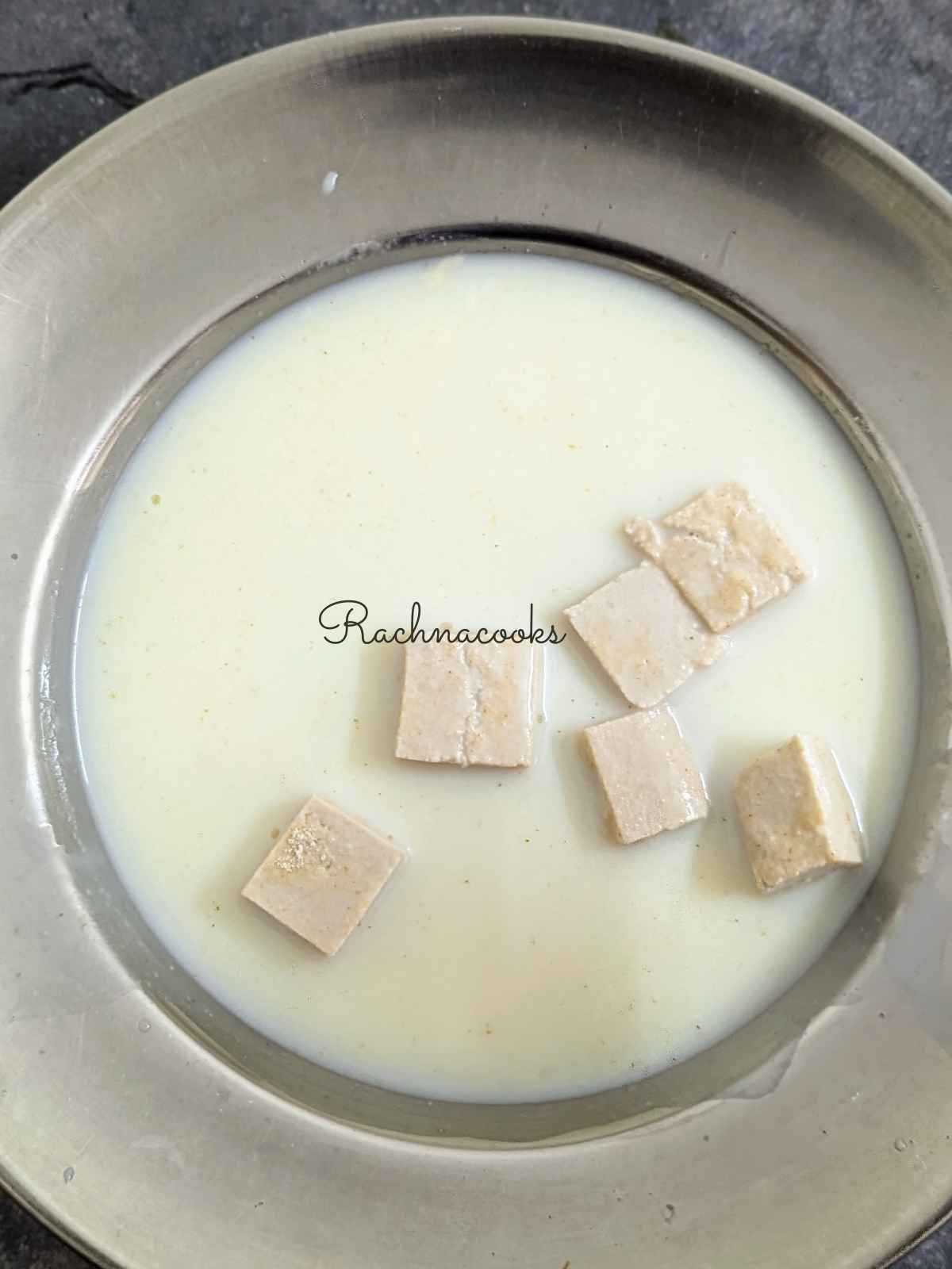 tofu bites dipped in vegan milk in a shallow plate
