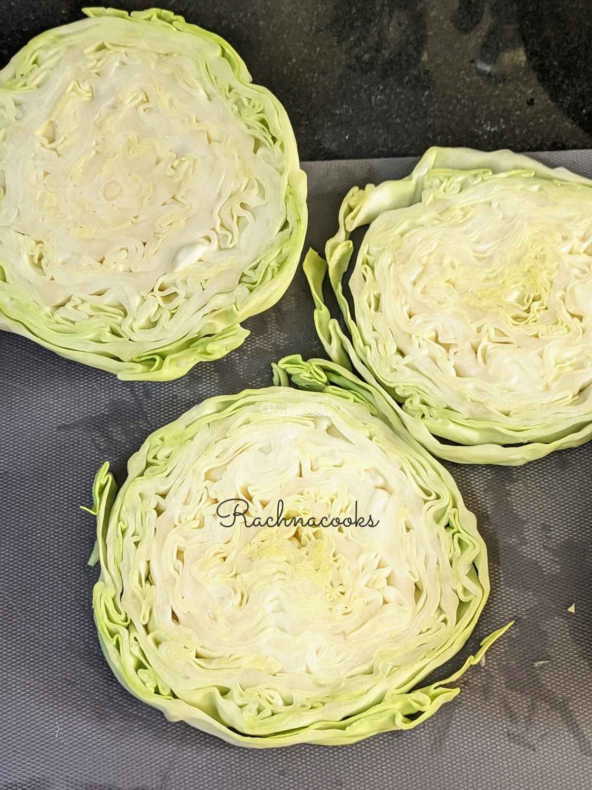 3 cabbage steaks on a chopping surface.