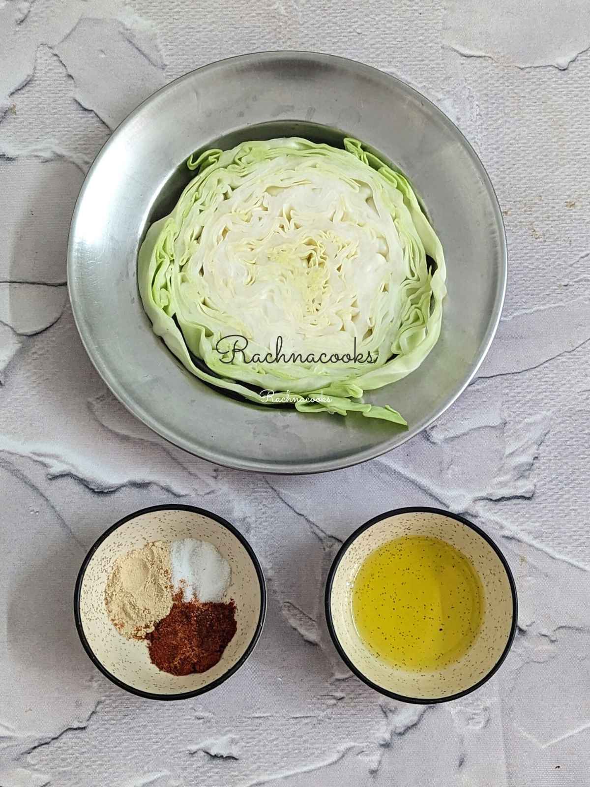 Cabbage steak in a shallow plate, olive oil and seasonings in bowls.