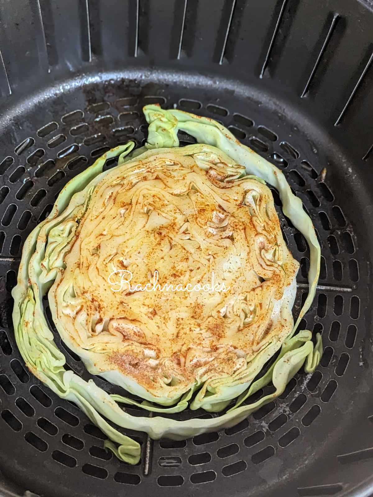 Seasoned cabbage steak placed in air fryer basket.